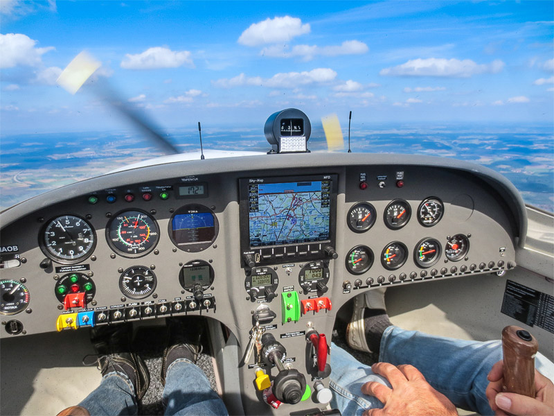 Innenraum eines Kleinflugzeugs mit Blick auf das Armaturenbrett und die Außenlandschaft