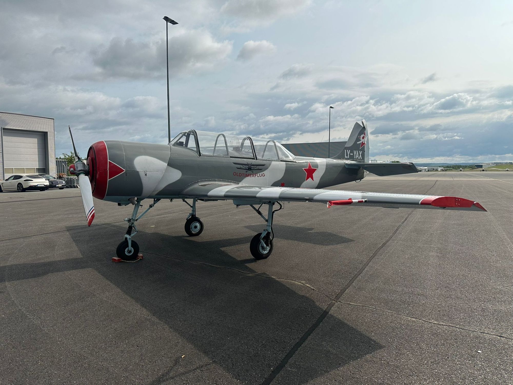 Tribünenflugzeug mit rotem Stern auf Asphaltfläche vor Hanga